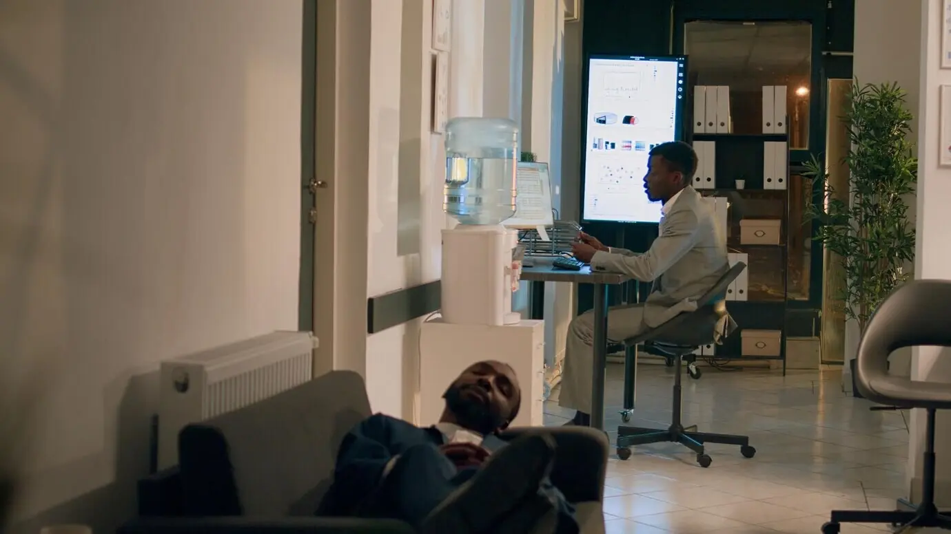 Сотрудник дремлет на офисном диване.